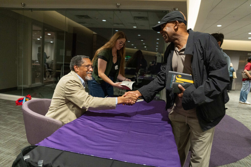 Percival Everett shakes hands with a guest.