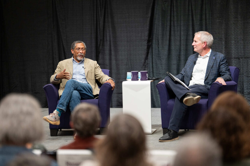 Percival Everett chatting while seated on stage with President Rob Vischer.