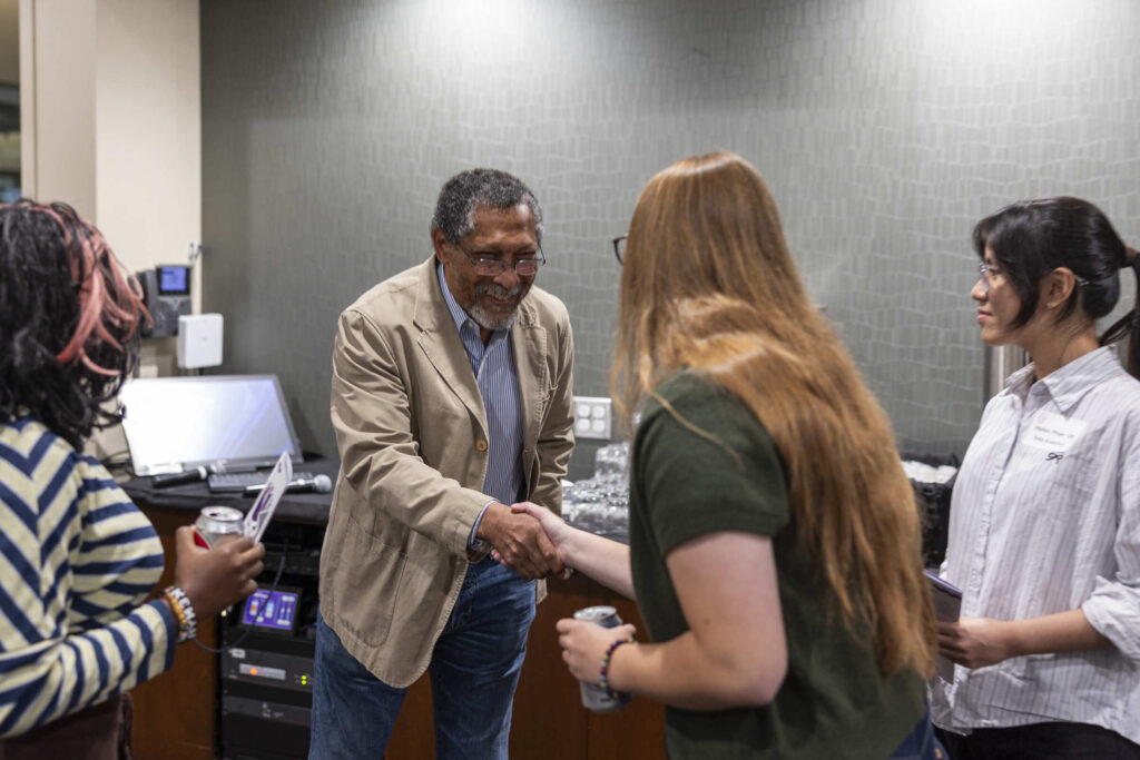Percival Everett extends his hand while meeting a student.
