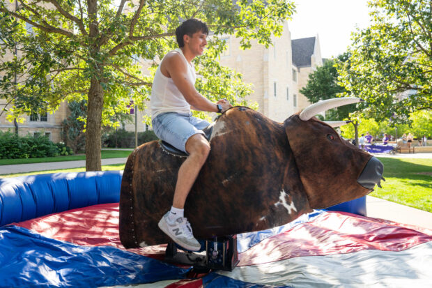 A student ride the mechanical bull at a Pack the Quad event.