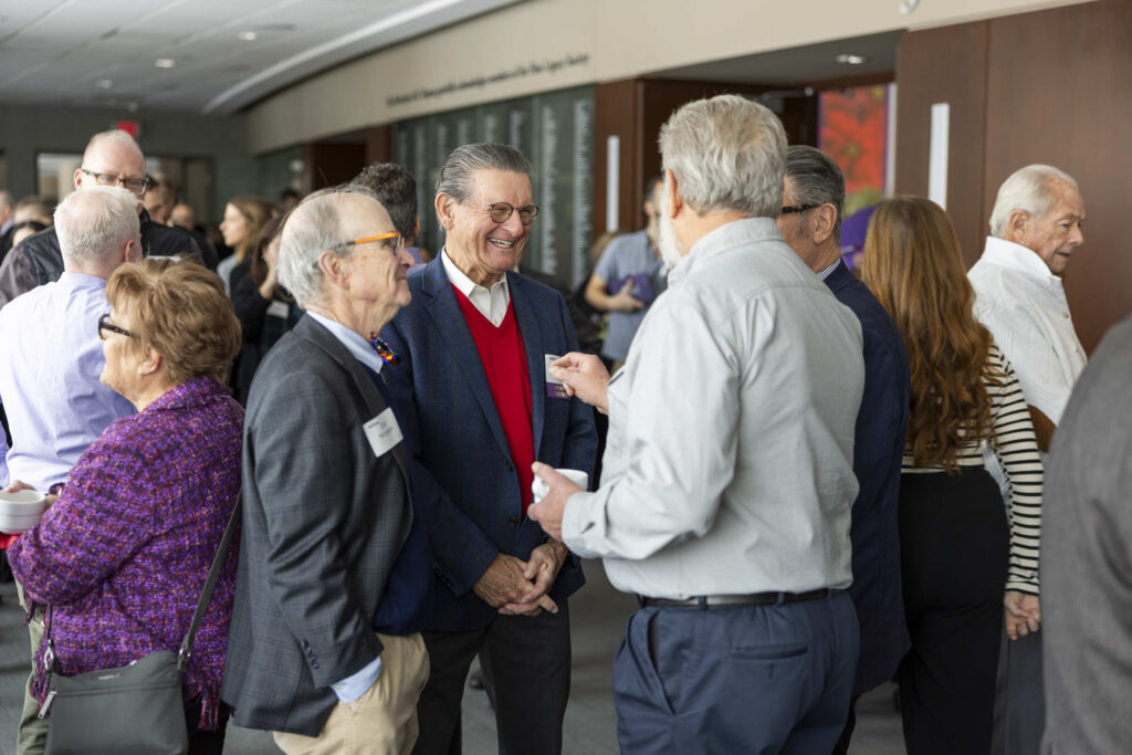 A group of alums standings and speaking to each other at a luncheon.