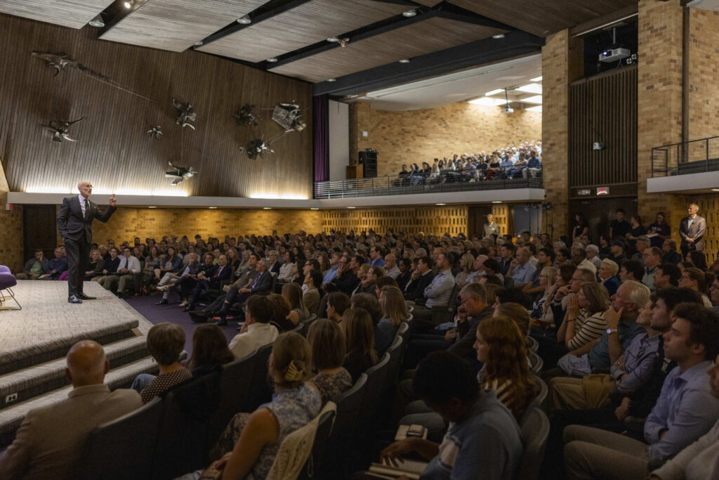 Arthur Brooks stands on the stage and speaks to the audience in the OEC Auditorium. 