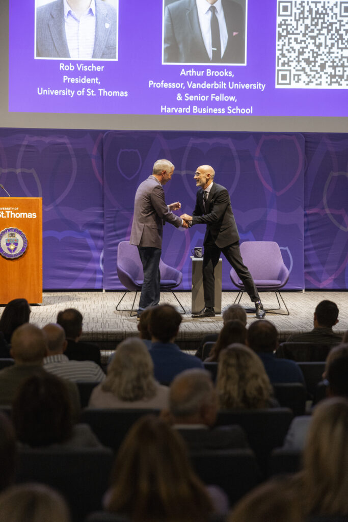 President Rob Vischer shakes hands with Arthur Brooks on the stage at Arthur Brooks' talk. 