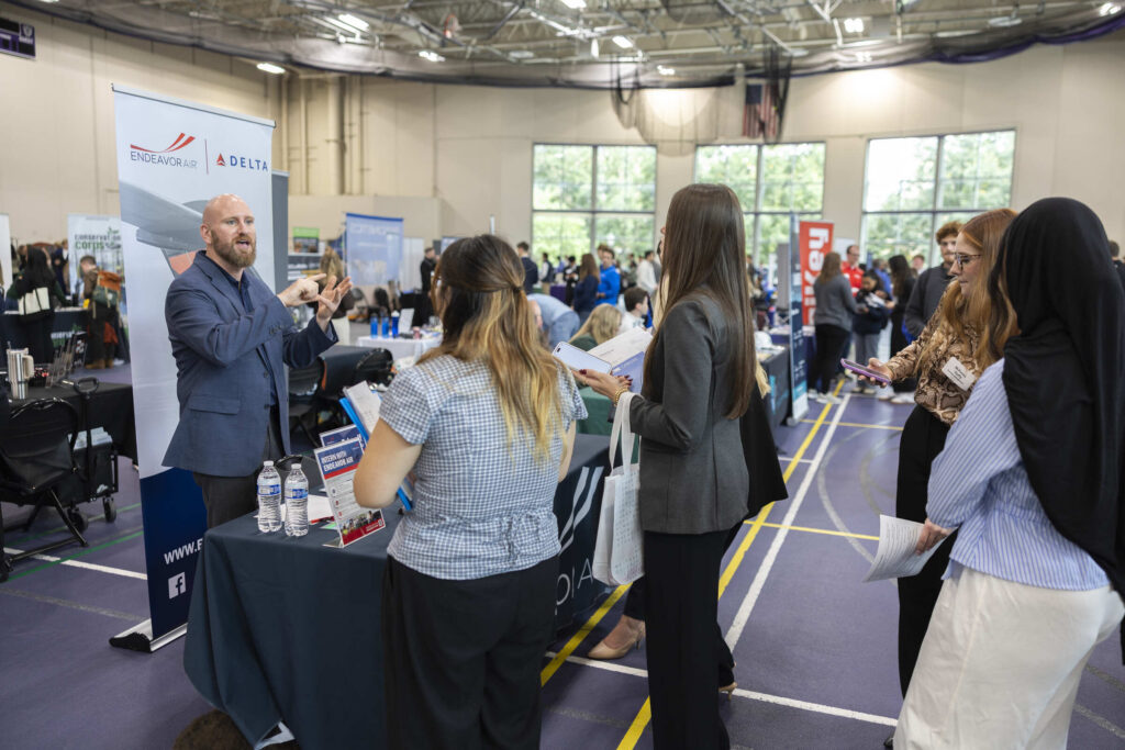 A recruiter speaks to students from the Delta booth at the career fair.
