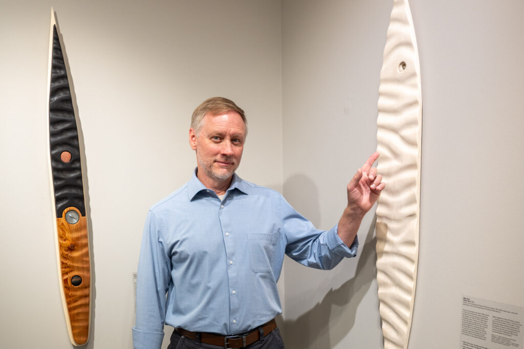 Mike Klein posing next to his artworks "Steamboat Northerner" and "White."