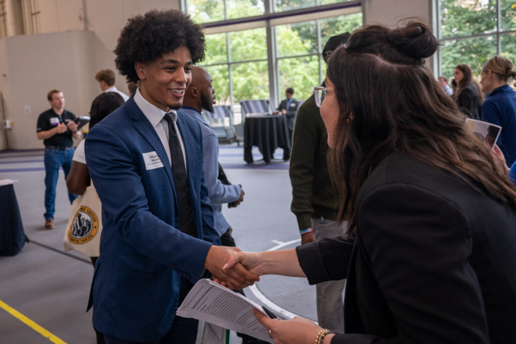 Ofgeha Assefa '28 shakes hands with a recruiter at a career fair.